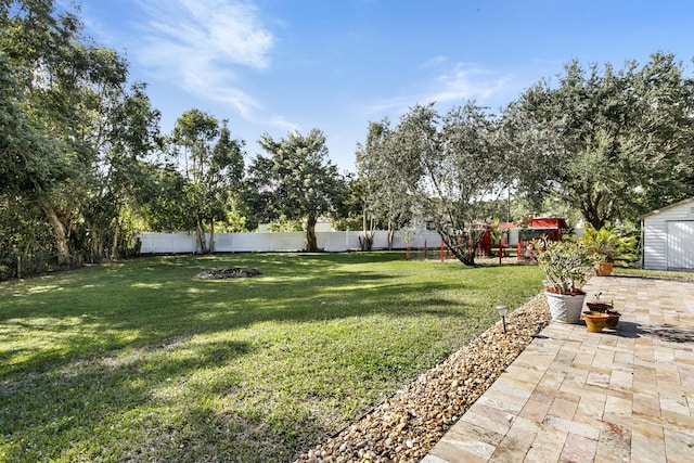 view of yard with a storage unit, a playground, and a patio area