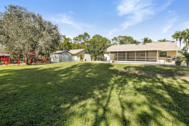 view of yard featuring a sunroom and a storage unit