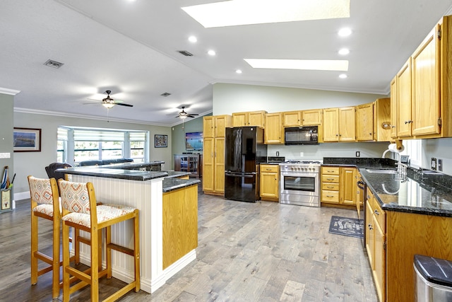 kitchen with sink, a kitchen bar, ornamental molding, black appliances, and light hardwood / wood-style flooring