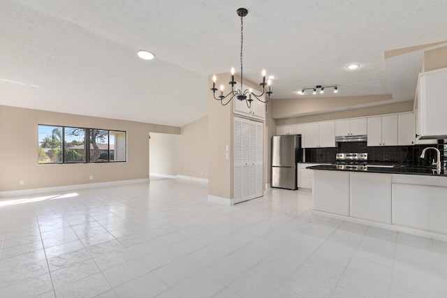 kitchen with pendant lighting, appliances with stainless steel finishes, white cabinetry, decorative backsplash, and vaulted ceiling