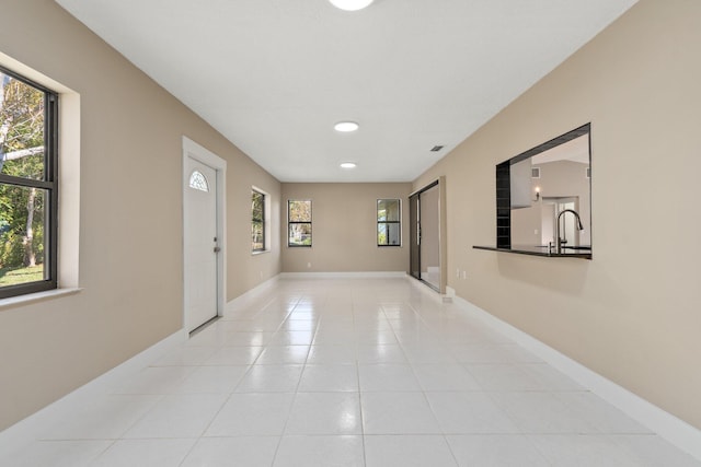 hall featuring sink and light tile patterned floors