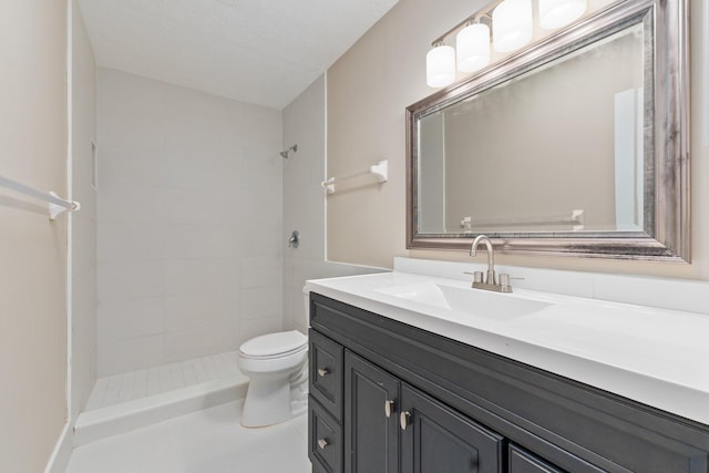 bathroom with vanity, a textured ceiling, toilet, and tiled shower