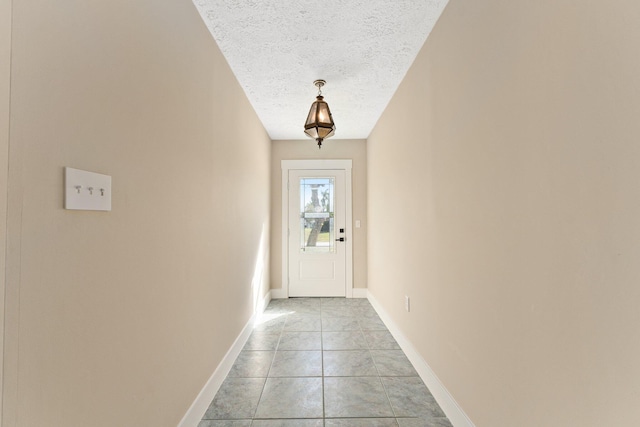 doorway to outside featuring a textured ceiling and light tile patterned flooring