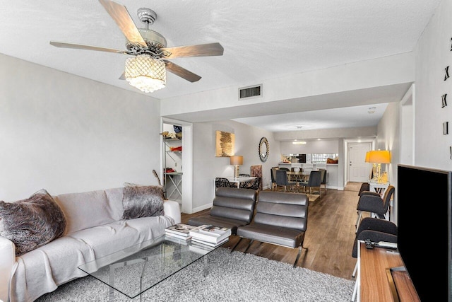 living room with ceiling fan, hardwood / wood-style floors, and a textured ceiling