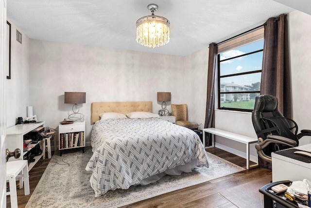 bedroom with an inviting chandelier and dark wood-type flooring