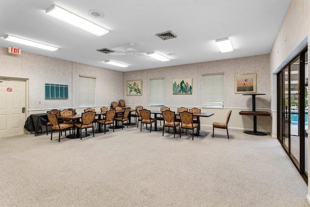 carpeted dining area with ceiling fan and a textured ceiling