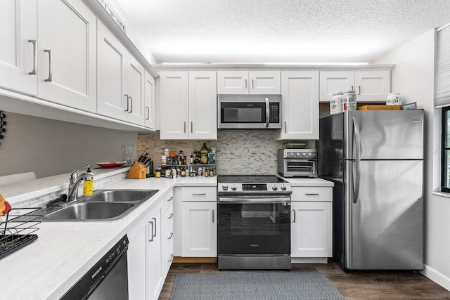 kitchen with sink, appliances with stainless steel finishes, white cabinetry, dark hardwood / wood-style flooring, and decorative backsplash