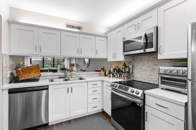 kitchen with sink, tasteful backsplash, a textured ceiling, stainless steel appliances, and white cabinets