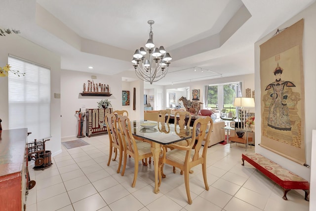 tiled dining space with an inviting chandelier and a tray ceiling