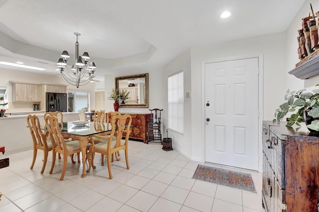 dining area featuring a raised ceiling, light tile patterned flooring, and a chandelier