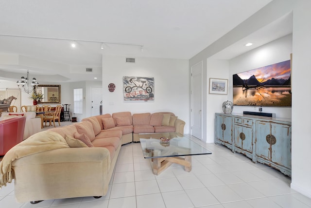 tiled living room featuring track lighting and a notable chandelier