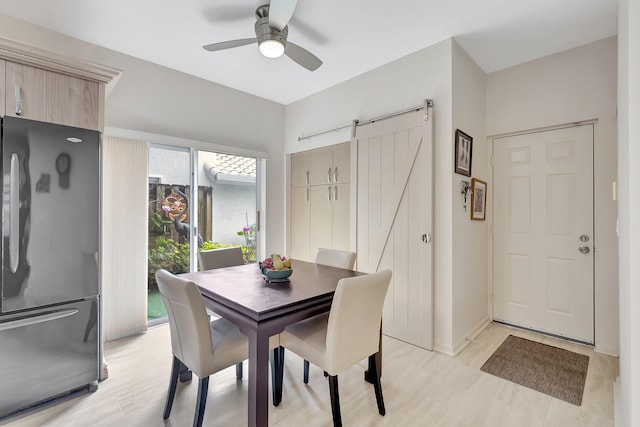 dining area with a barn door and ceiling fan