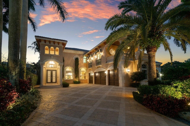 mediterranean / spanish house featuring an attached garage, decorative driveway, and stucco siding