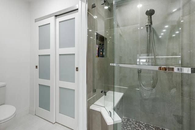 bathroom featuring a shower with door and toilet