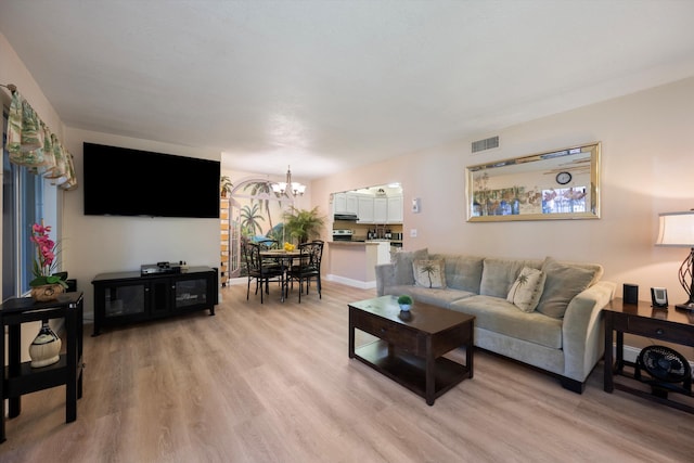 living room featuring a chandelier and light wood-type flooring