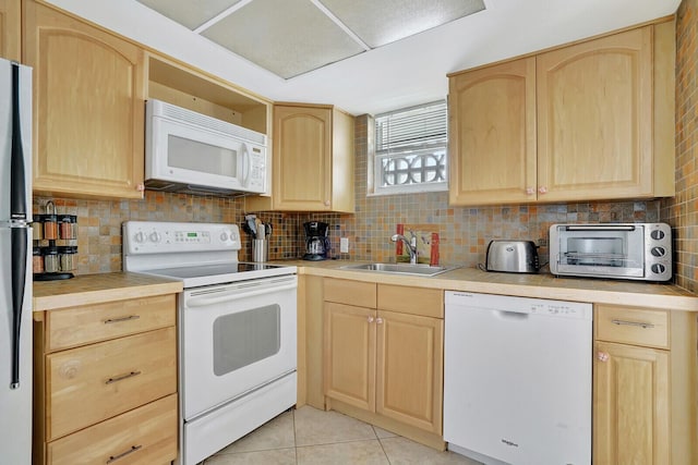 kitchen with sink, white appliances, and light brown cabinets