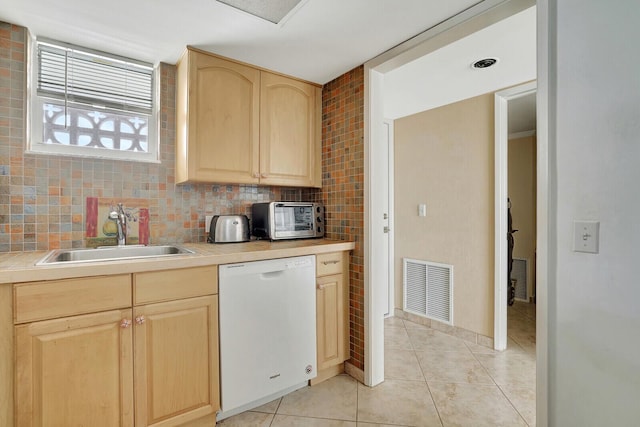 kitchen featuring light brown cabinetry, sink, light tile patterned floors, dishwasher, and decorative backsplash