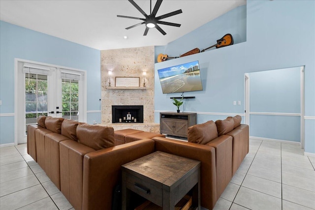 living room with french doors, light tile patterned flooring, vaulted ceiling, ceiling fan, and a fireplace