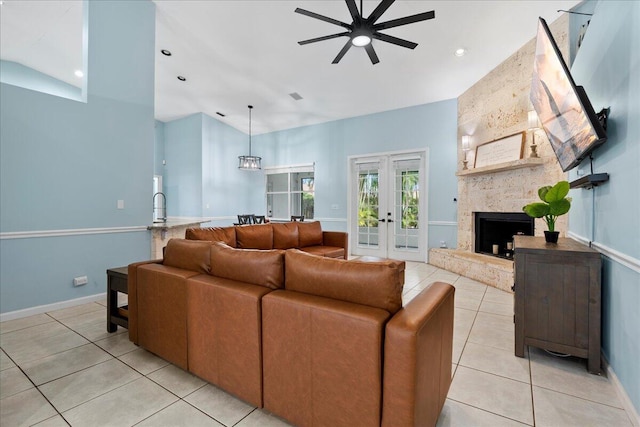 living room featuring french doors, light tile patterned flooring, sink, ceiling fan, and a fireplace