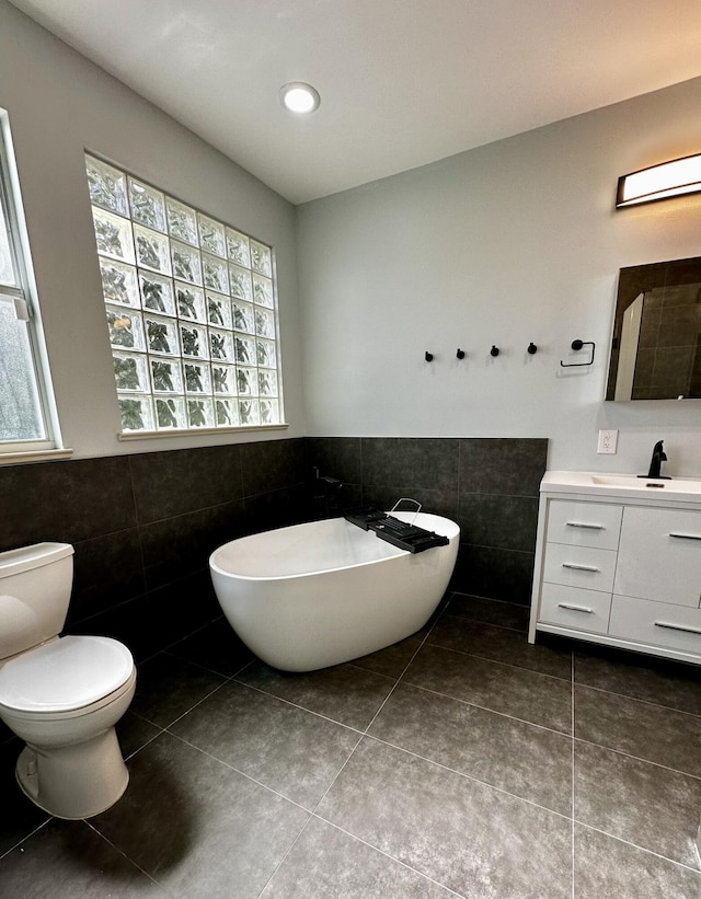 bathroom featuring vanity, tile walls, tile patterned floors, and toilet