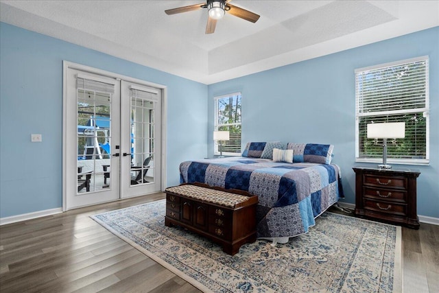 bedroom with french doors, wood-type flooring, a raised ceiling, ceiling fan, and access to exterior