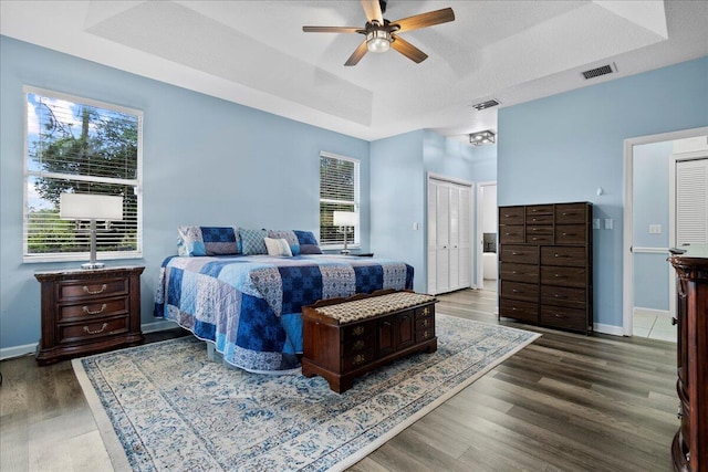 bedroom featuring a raised ceiling, ceiling fan, a textured ceiling, and dark hardwood / wood-style flooring