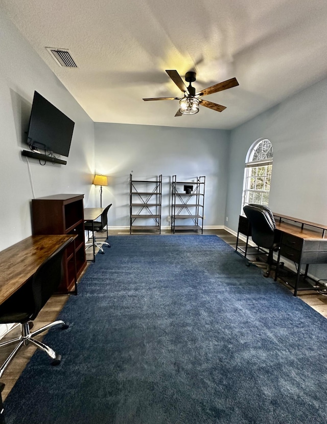 carpeted office space featuring ceiling fan and a textured ceiling