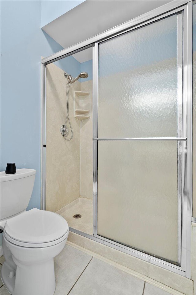 bathroom featuring toilet, tile patterned floors, and a shower with shower door