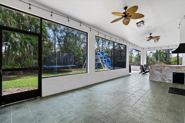 unfurnished sunroom with ceiling fan