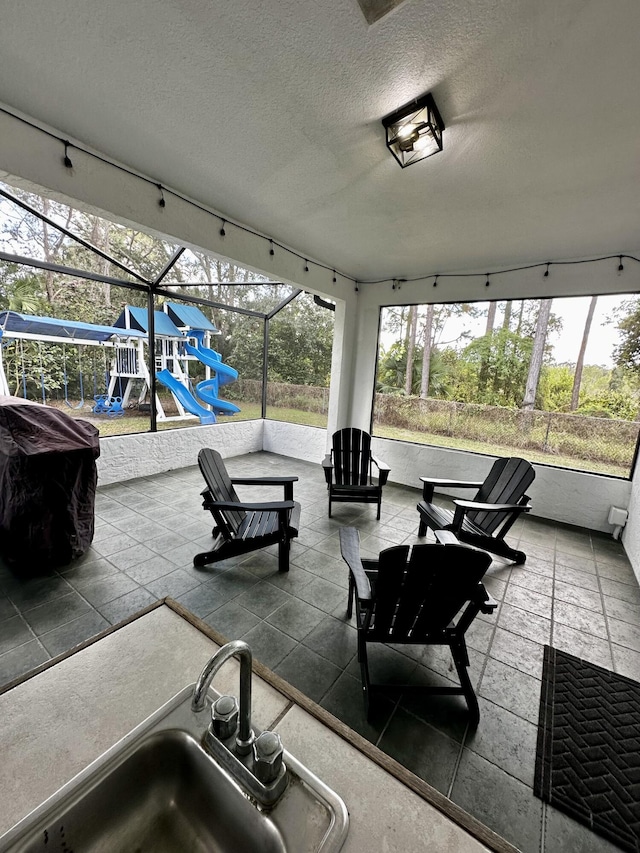 view of patio / terrace featuring a playground, a lanai, and sink