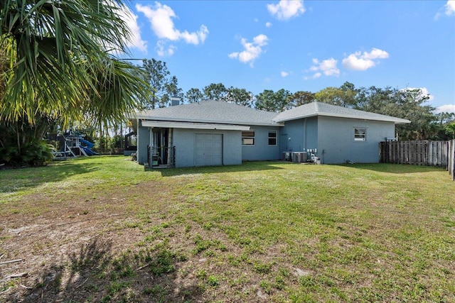 back of property with central AC unit, a yard, and a playground