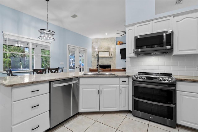 kitchen featuring sink, white cabinetry, light stone counters, appliances with stainless steel finishes, and kitchen peninsula