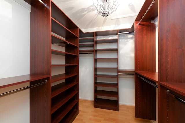 spacious closet with a notable chandelier and light wood-type flooring