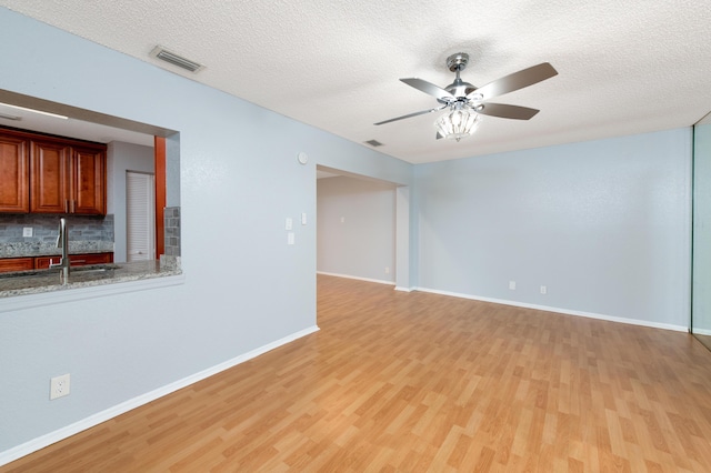 unfurnished room with ceiling fan, sink, light hardwood / wood-style floors, and a textured ceiling