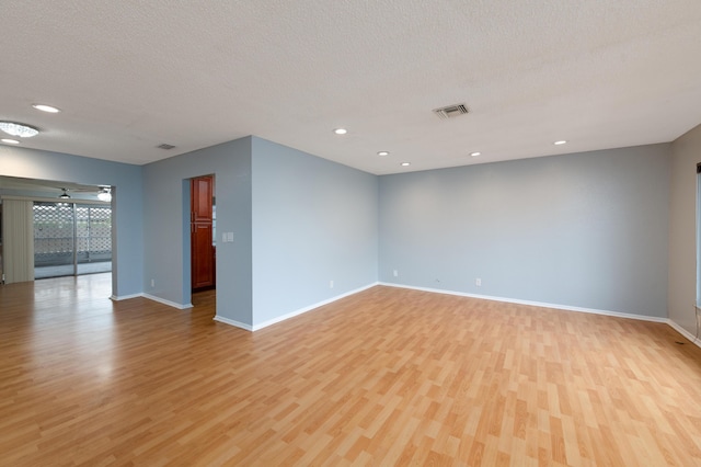 unfurnished room featuring light hardwood / wood-style floors and a textured ceiling