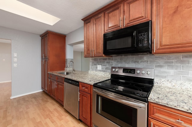 kitchen featuring appliances with stainless steel finishes, sink, decorative backsplash, light hardwood / wood-style floors, and light stone counters