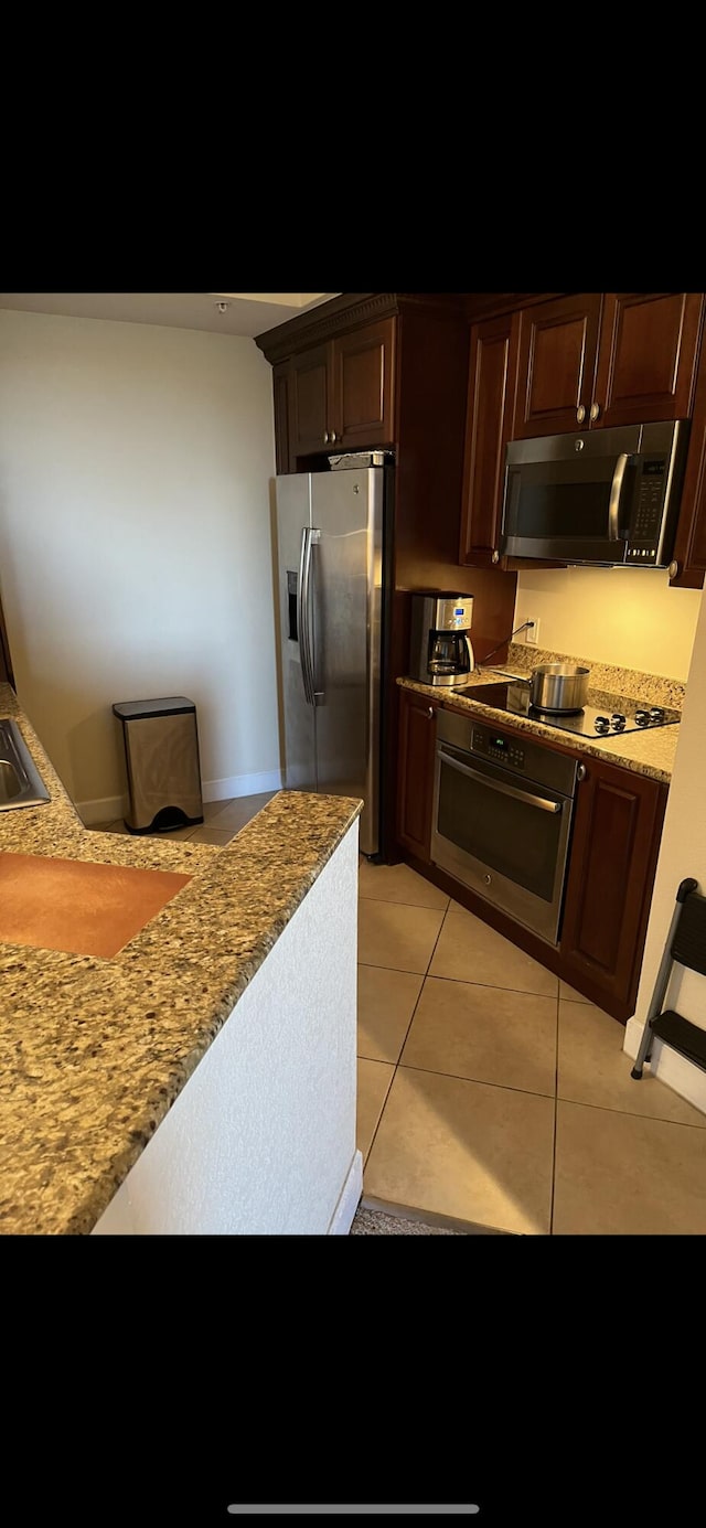 kitchen featuring light stone counters, stainless steel appliances, and light tile patterned floors