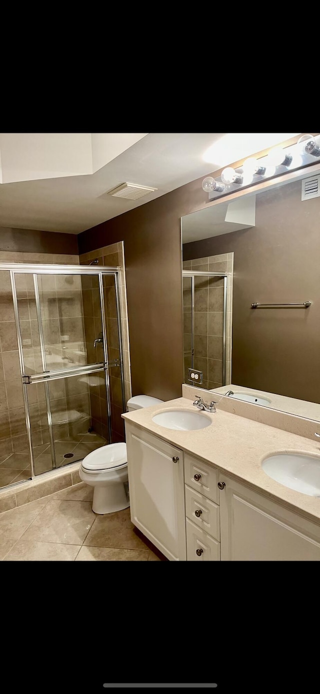 bathroom with tile patterned floors, toilet, a shower with shower door, and vanity