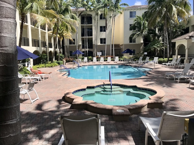 view of swimming pool featuring a hot tub and a patio area