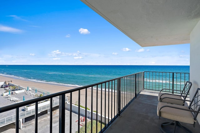 balcony with a water view and a view of the beach