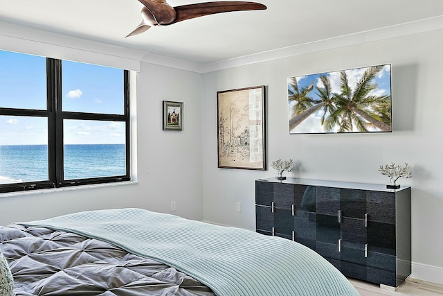 bedroom with ornamental molding, light hardwood / wood-style floors, and a water view