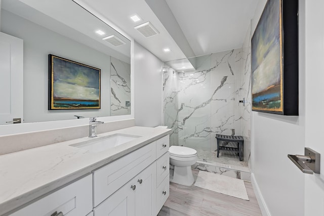 bathroom with vanity, tiled shower, and toilet