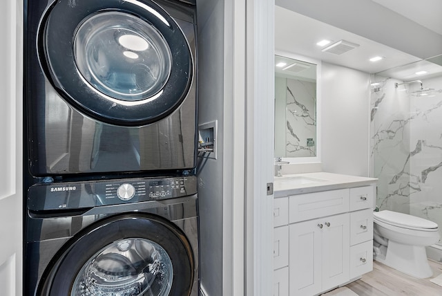 laundry area featuring stacked washer / drying machine, sink, and light wood-type flooring