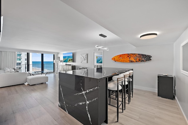 kitchen featuring expansive windows, a kitchen breakfast bar, and light hardwood / wood-style flooring