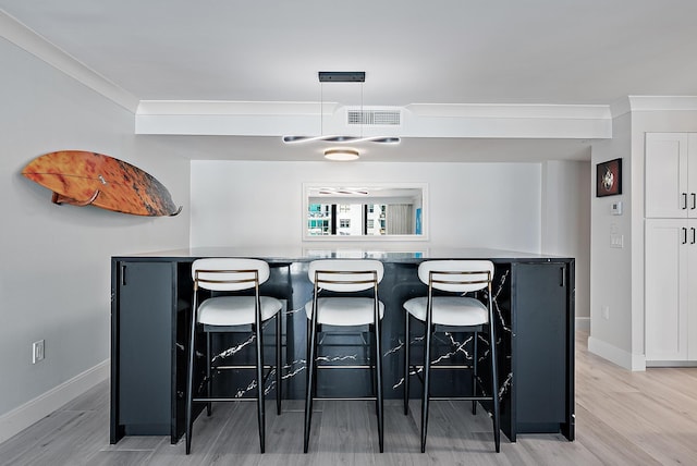 bar featuring ornamental molding and light hardwood / wood-style flooring