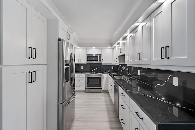 kitchen with white cabinetry, sink, decorative backsplash, dark stone counters, and stainless steel appliances