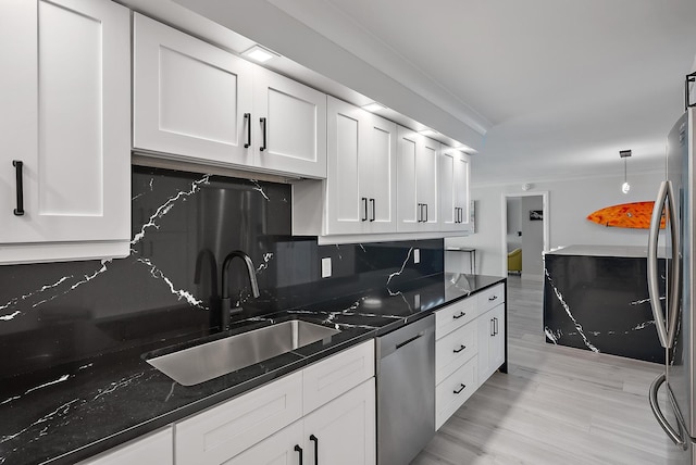 kitchen featuring sink, appliances with stainless steel finishes, white cabinets, decorative light fixtures, and dark stone counters