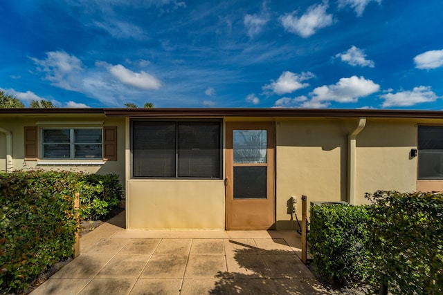 view of exterior entry with a patio area