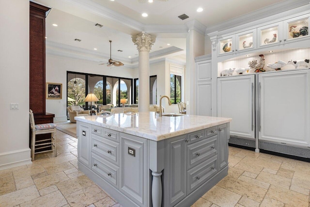kitchen with a ceiling fan, gray cabinets, stone tile flooring, and a sink