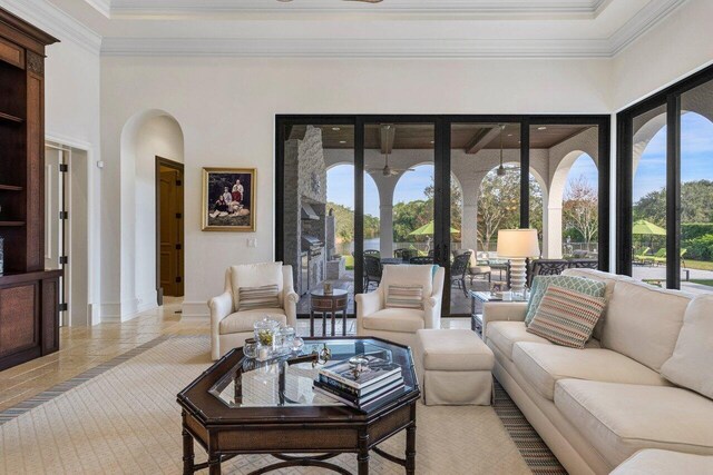 living room with a towering ceiling, arched walkways, and crown molding